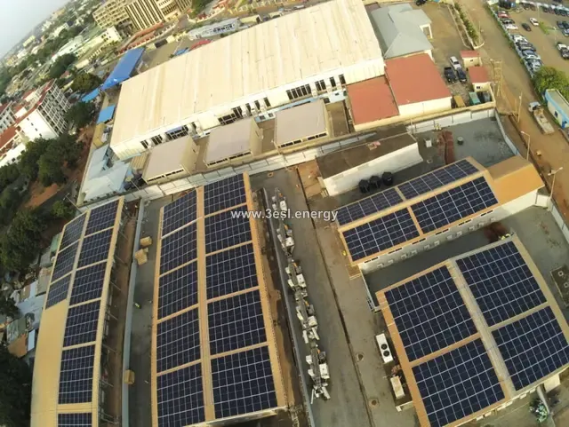 Aerial view of a commercial site with solar arrays covering several adjoining roofs.