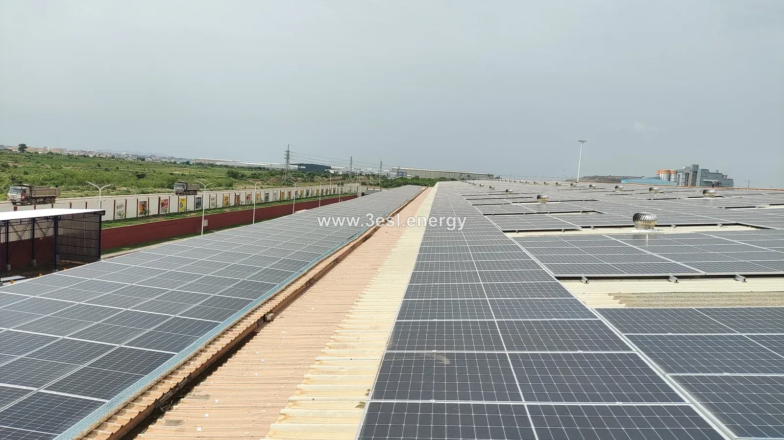 Solar panels covering a large industrial rooftop, with a maintenance walkway between the arrays.